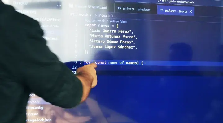 Profesor enseñando código JavaScript en una pantalla